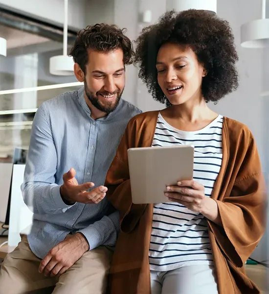 um homem e uma mulher conversando olhando para um tablet