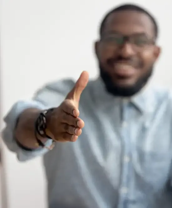 homem com camisa social sorrindo e estendendo a mão em um gesto de aperto de mão