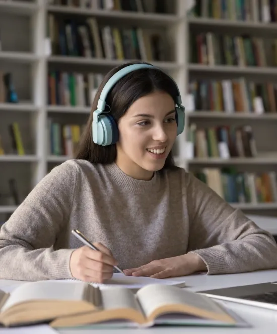 mulher com fone de ouvido em uma biblioteca mexendo em notebook