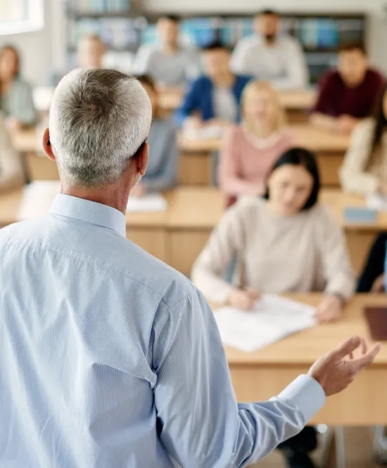 homem professor em frente a uma turma de adultos dentro de uma sala de aula