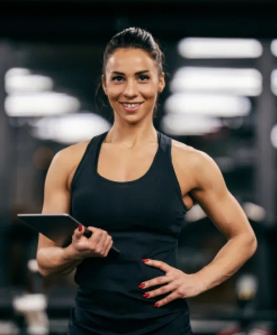 mulher profissional de gestão desportiva e de lazer com regata preta em academia sorrindo