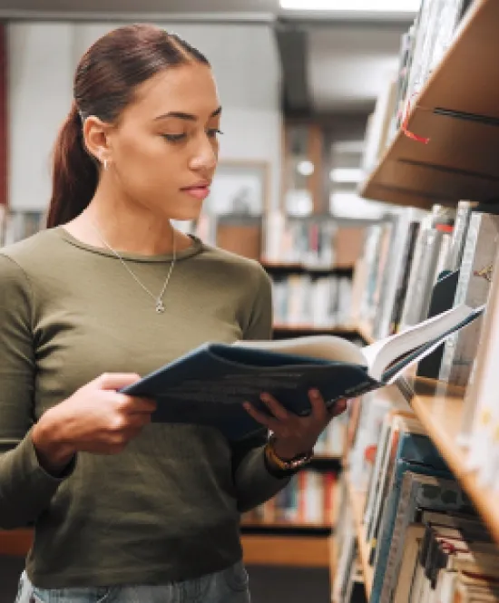 Mulher lê livro em biblioteca