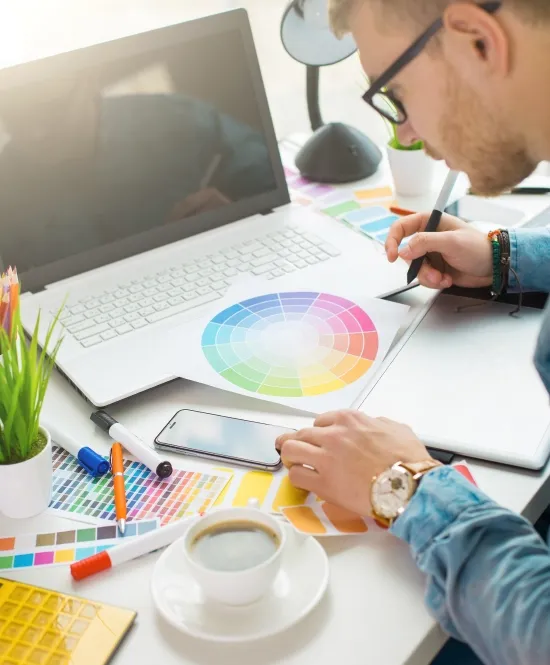 designer gráfico desenhando e analisando cores em cima de uma mesa