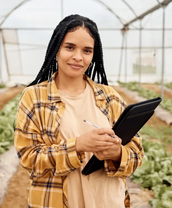 mulher agrônoma com prancheta em mãos dentro de uma estufa de plantação