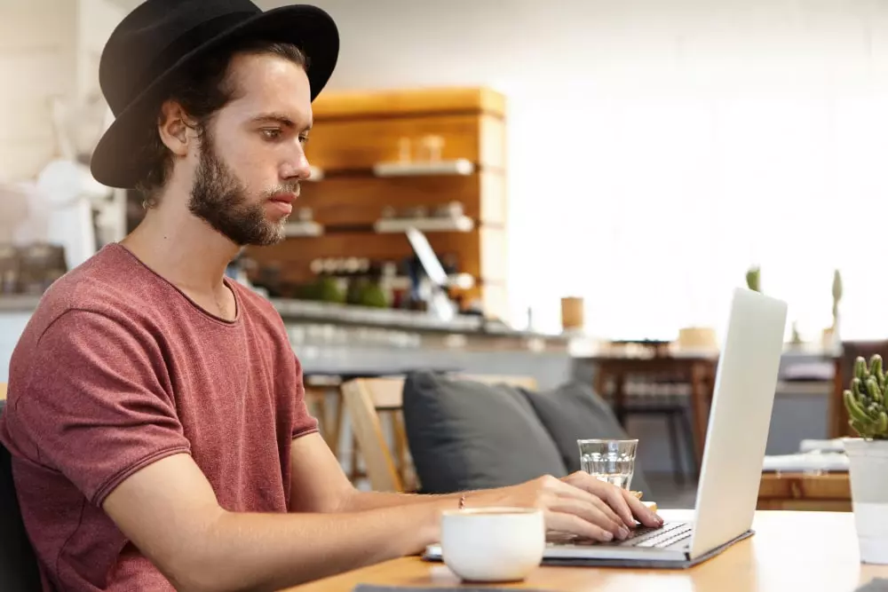 homem de chapeu olhando notebook