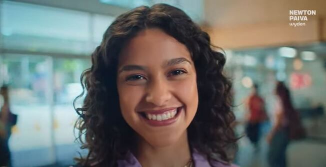 jovem sorrindo com a logo da newton paiva