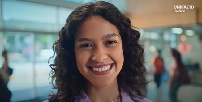 jovem sorrindo com a logo unifacid